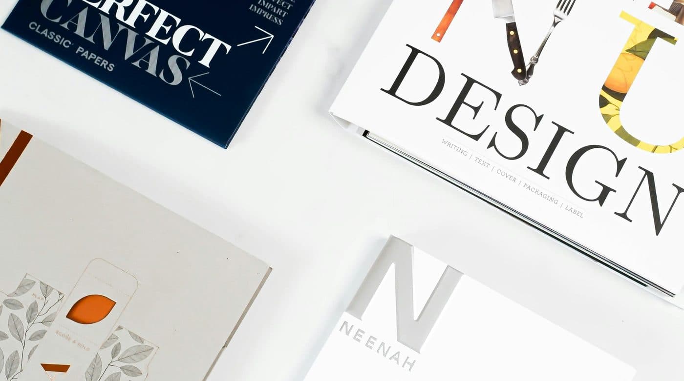 Printed brochures, a paper sample book and colour swatches laid out on a studio desk