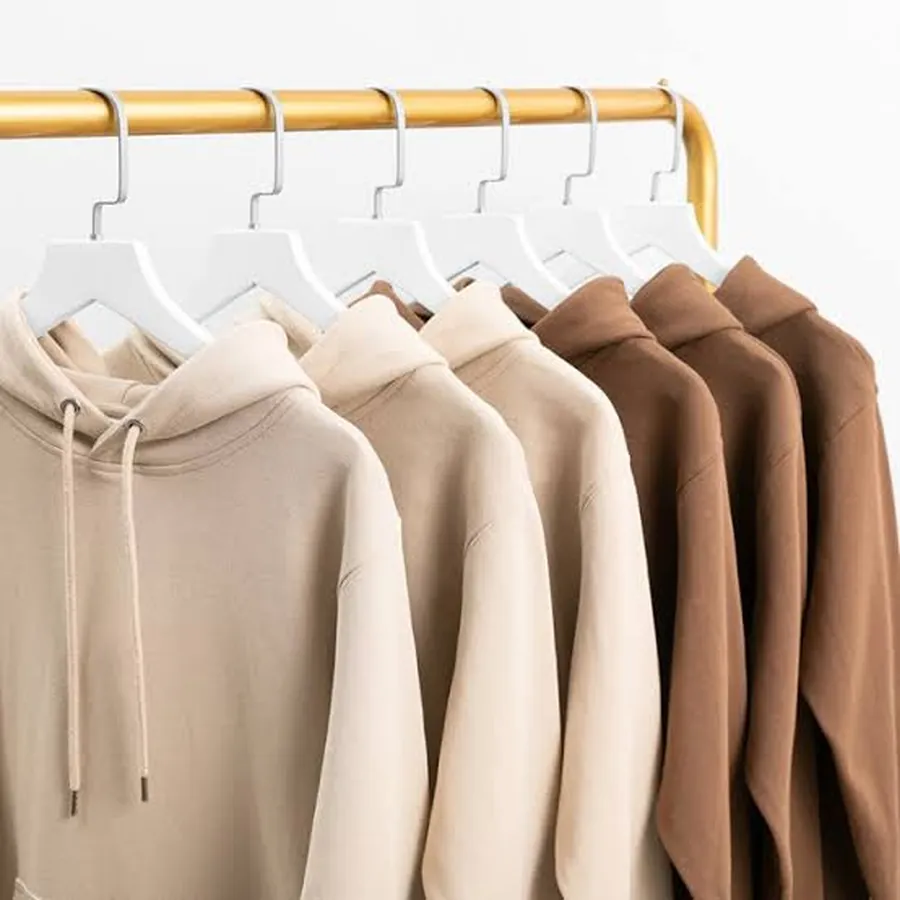 Six plain hoodies in sand and brown shades hanging in a row on white hangers