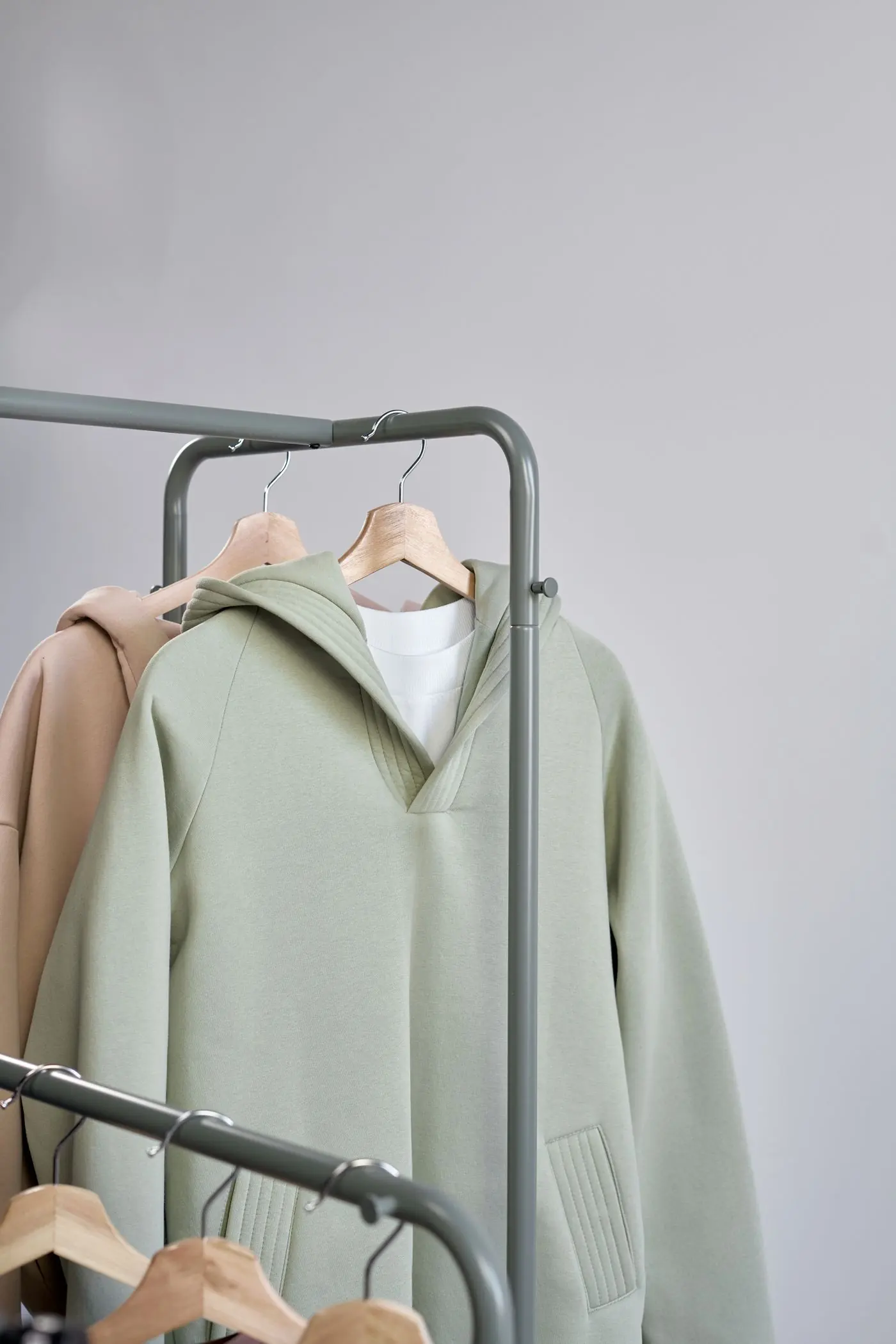 A sage green hoodie hanging on a clothes rail
